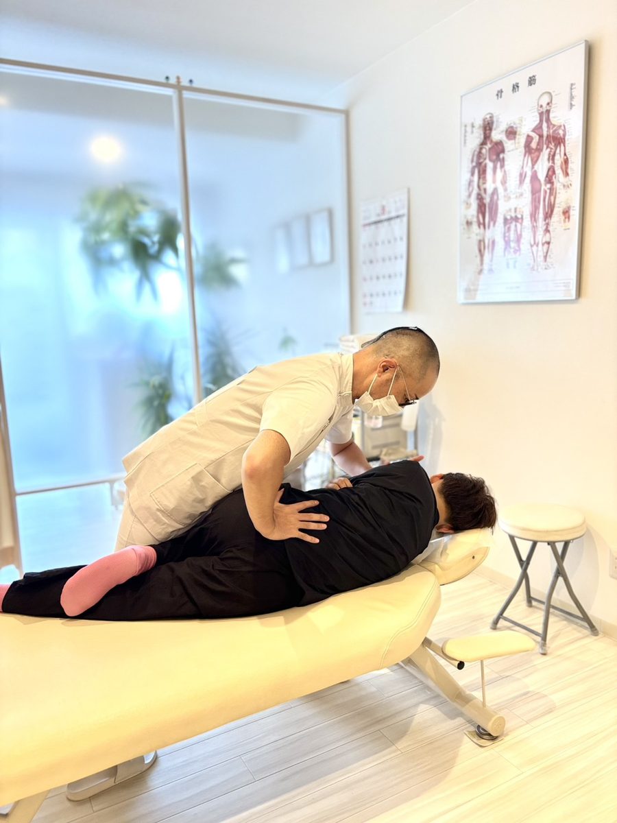 強く押さない手技。腰に手を当てて力加減を確かめる院長